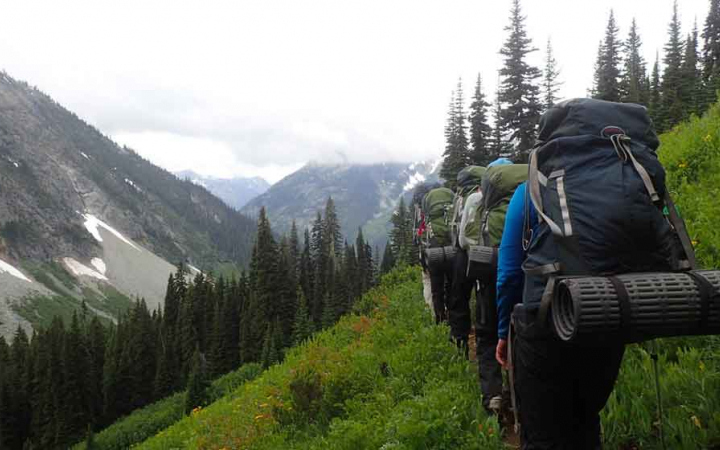 a group of teens crossing mountainous terrain on outdoor leadership course